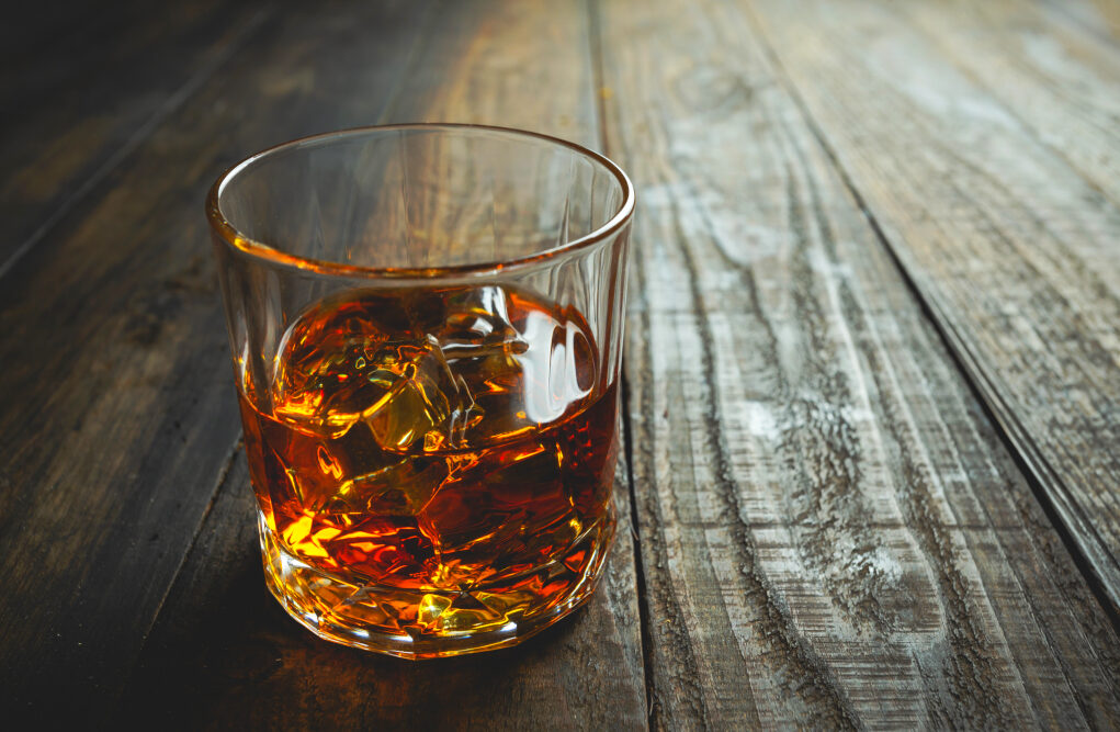 glasses of whiskey with ice cubes on wooden.