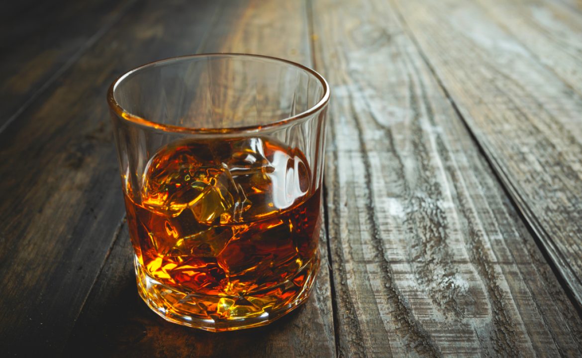glasses of whiskey with ice cubes on wooden.