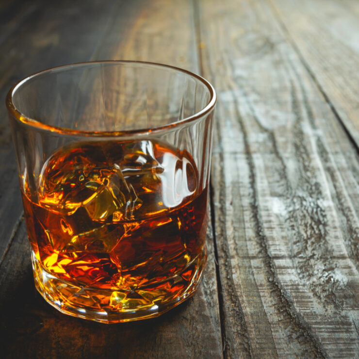 glasses of whiskey with ice cubes on wooden.